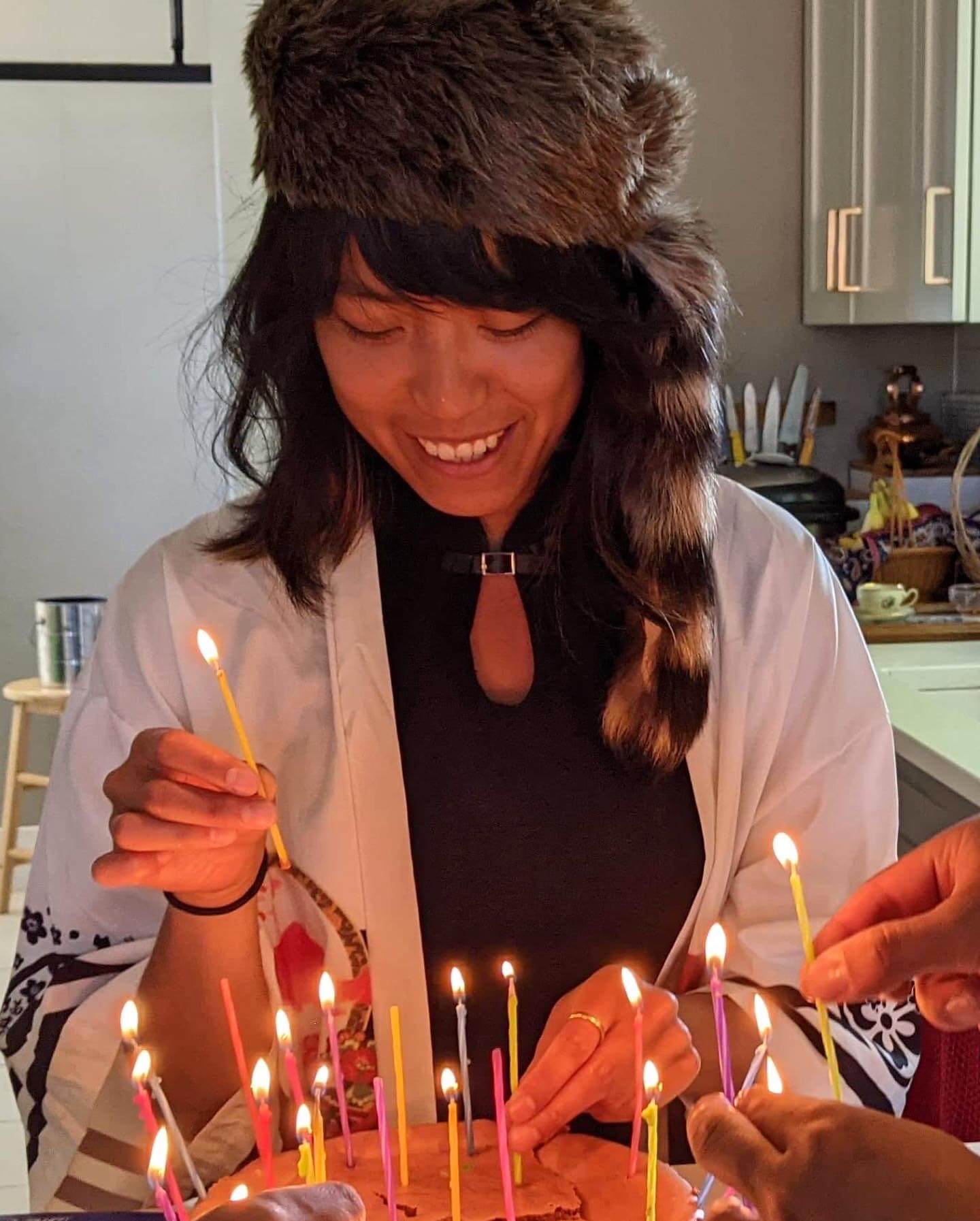 Alex in a racoon hat in front of a cake